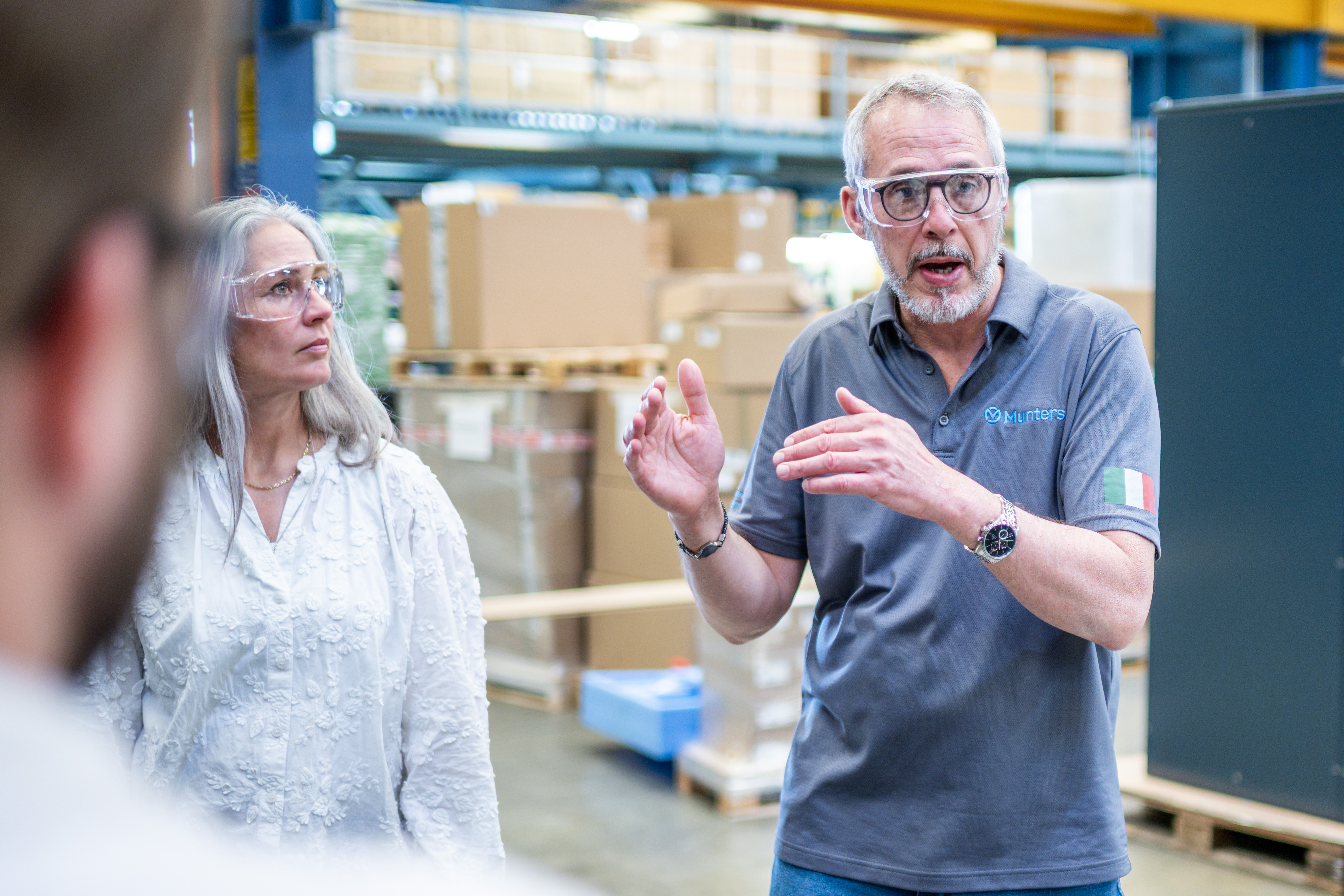 Munters employees discussing work on a manufacturing floor while wearing safety glasses