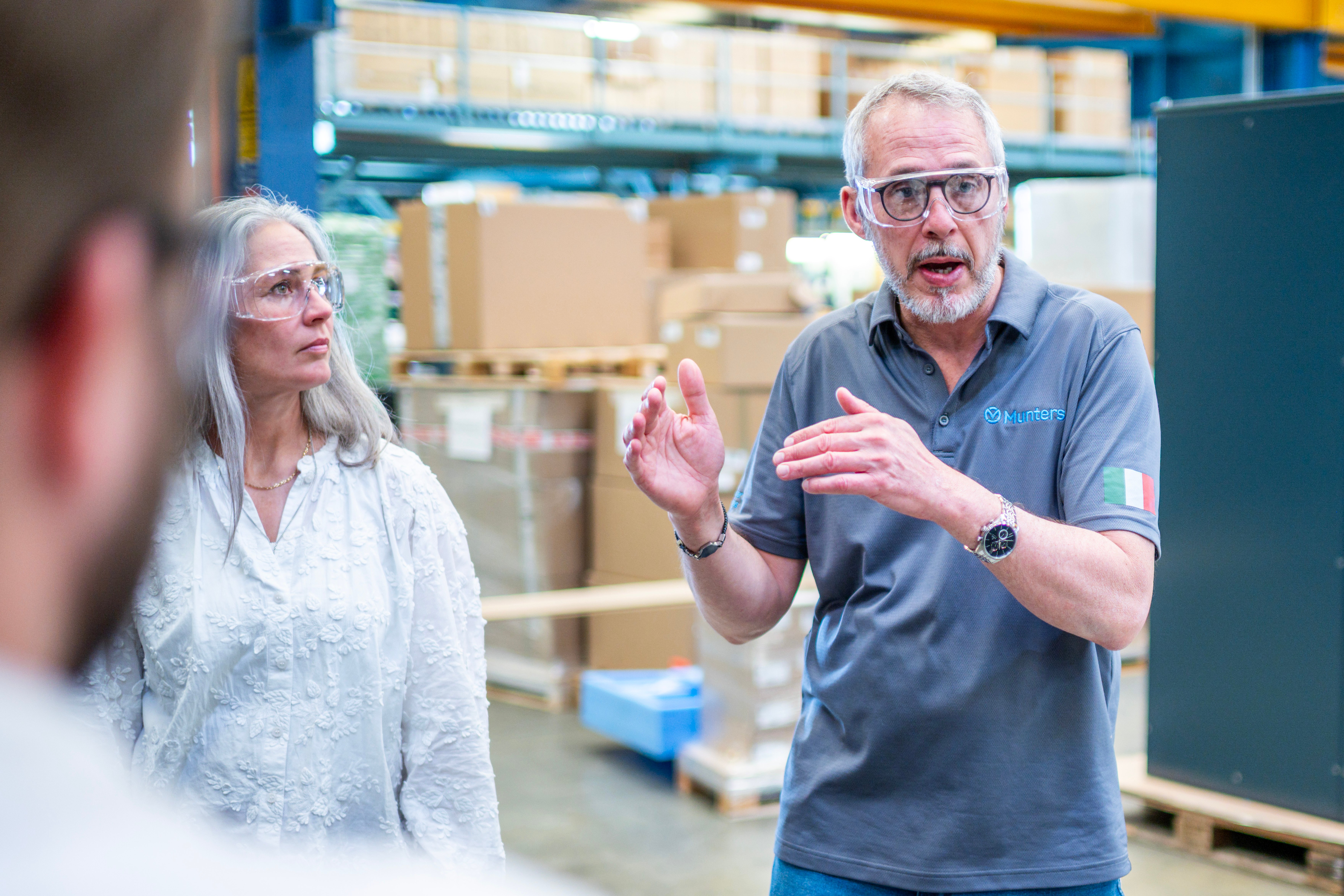 Munters employees discussing work on a manufacturing floor while wearing safety glasses
